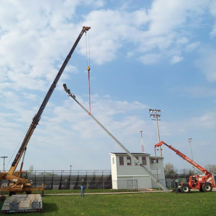 two cranes raising a light pole at the fair grounds