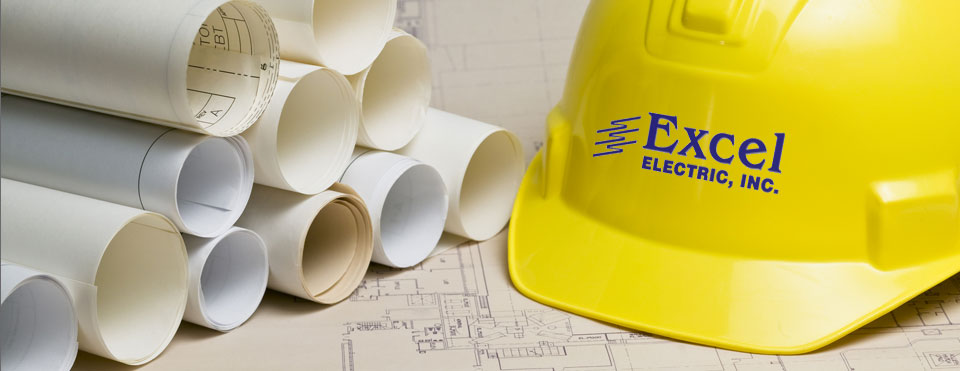 a yellow excel electric branded safety helmet sitting beside a stack of plans