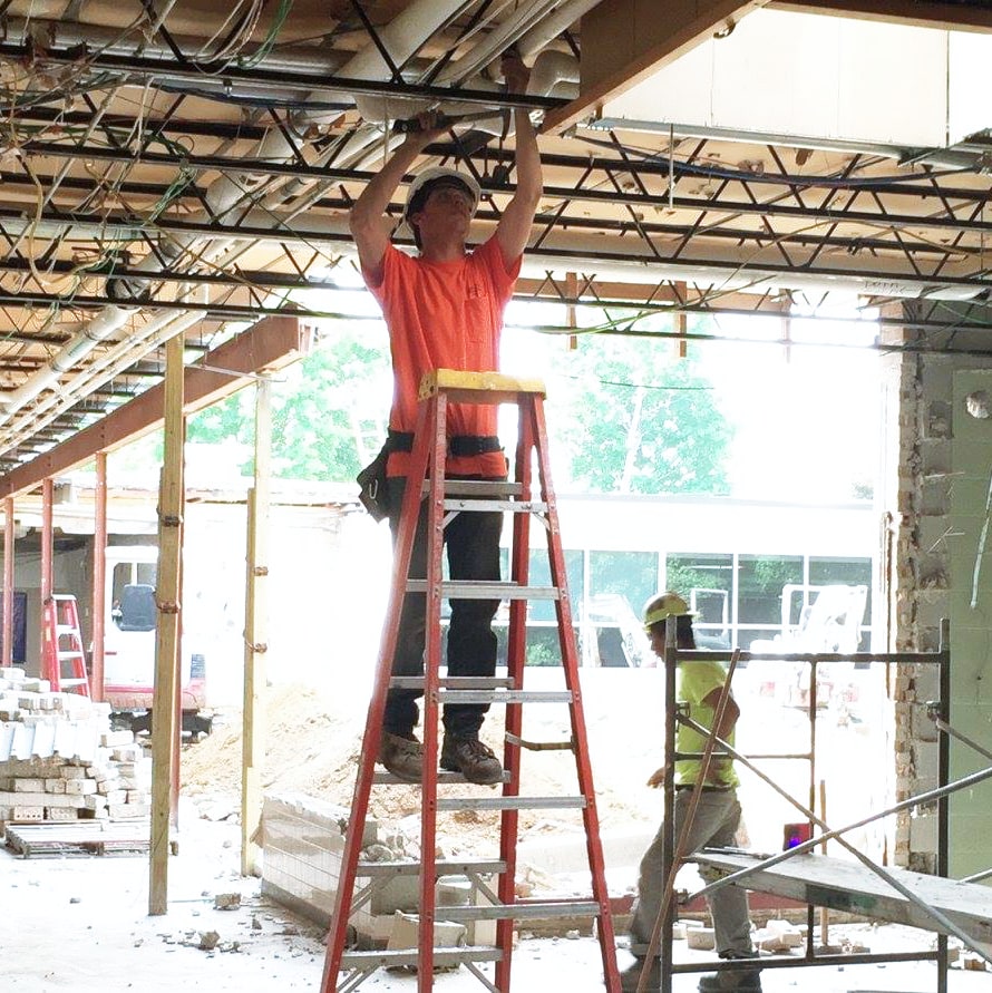 a person on a ladder running electrical wire